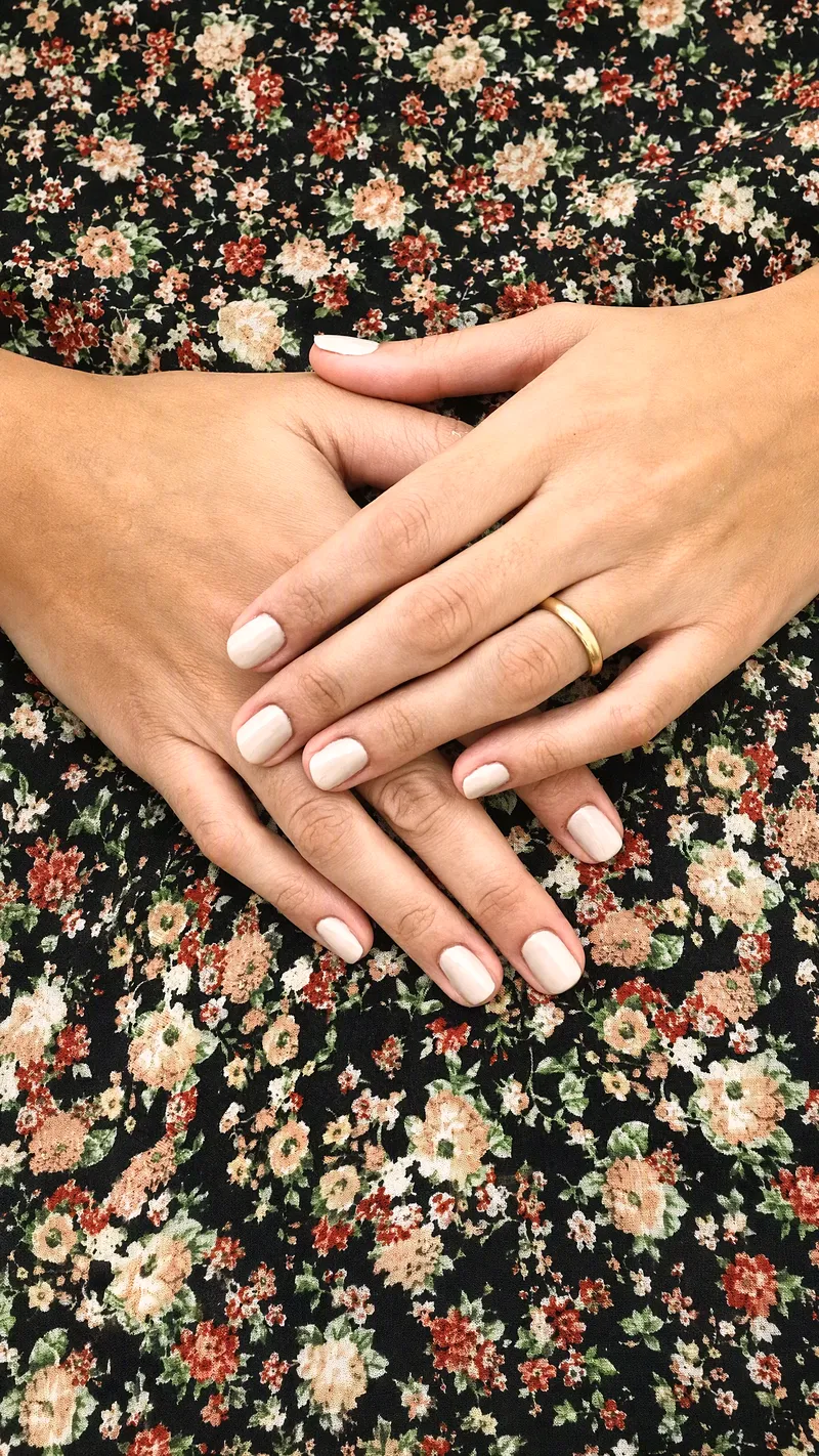 Le mani di una cliente con la fede e lo smalto nude, sul tessuto a fiori