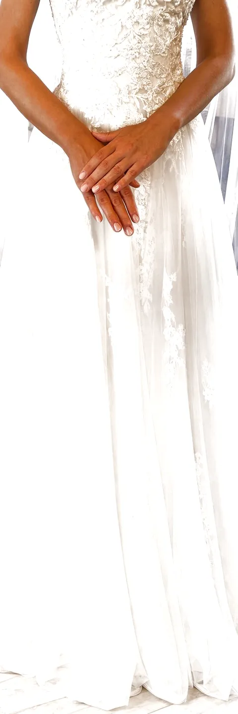 Una sposa con le mani incrociate, il corpetto di pizzo e la gonna di tulle fino all'orlo