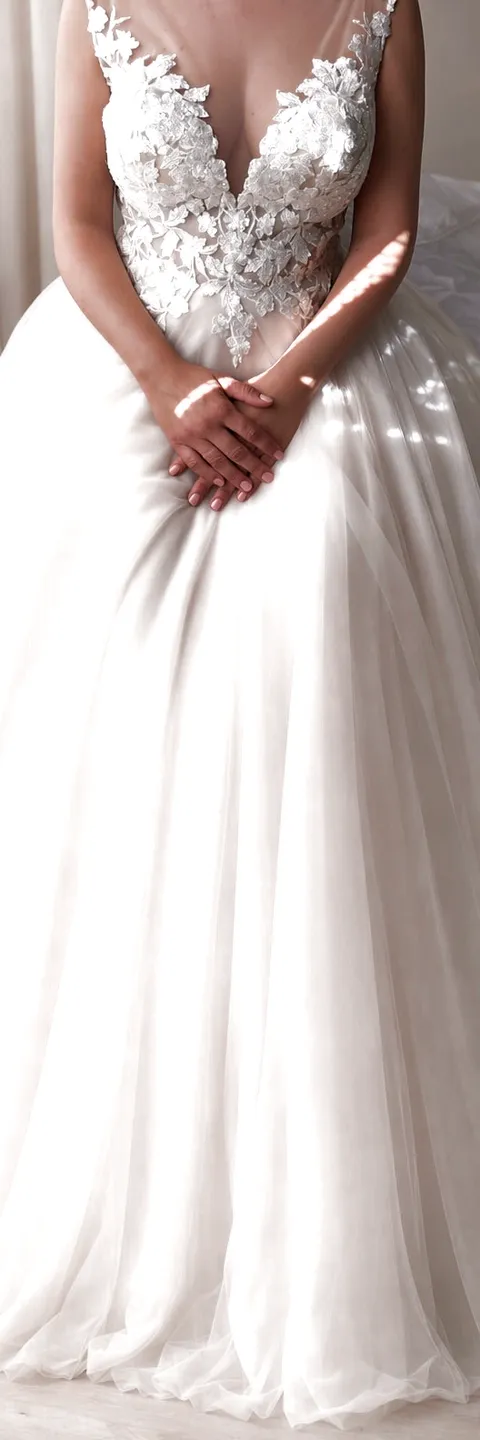 Una sposa nella luce della finestra, lo scollo di pizzo e la gonna di tulle